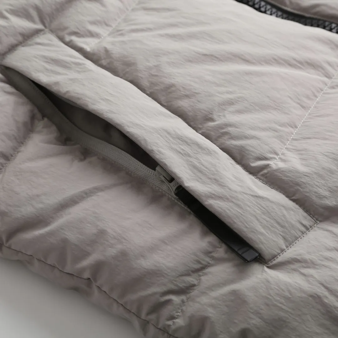P980 Canada Goose hooded down jacket Fabric selection: Weaved with 400T high-count yarn. After special water-repellent treatment, the surface forms a lotus leaf effect - raindrops will slide down in beads, and snow particles will fall off when touched. The tear resistance reaches 200N (approximately 20kg load-bearing), the light gray matte texture breaks the stereotype of "outdoor clothing = hardcore", and the soft luster presents a high-end matte effect under urban neon lights, seamlessly switching scenes from ski resorts to CBD office buildings.  Process 1: Use polyester woven ribbons as the base, and use high-precision computer embroidery to decorate the brand letters on the ribbons. The edges of the pattern are clear, the stitches are fine and even, and multiple layers of embroidery threads are stacked to enhance the three-dimensional effect.  Process 2: Precision thread reinforcement to prevent velvet drilling and ensure that the fluffy and resilient elasticity lasts as new.  Details: The embedded cuffs are three-dimensionally woven to form a "wavy" elastic structure, forming natural folds when fitting the wrist, increasing the contact area with the skin, thus improving the windproof effect. At the same time, micro-velvet treatment is added to the inside of the cuffs, which feels like a second layer of skin and avoids friction on the skin from metal zippers or hard fabrics.  90 national standard high-quality white duck down: selected high-loft down, weighing 240g, light and warm, with excellent temperature locking performance and good resilience.  Accessories: 1:1 customized armband, 1:1 customized zipper pendant, 1:1 customized elastic buckle, etc. SIZE: S M L XL